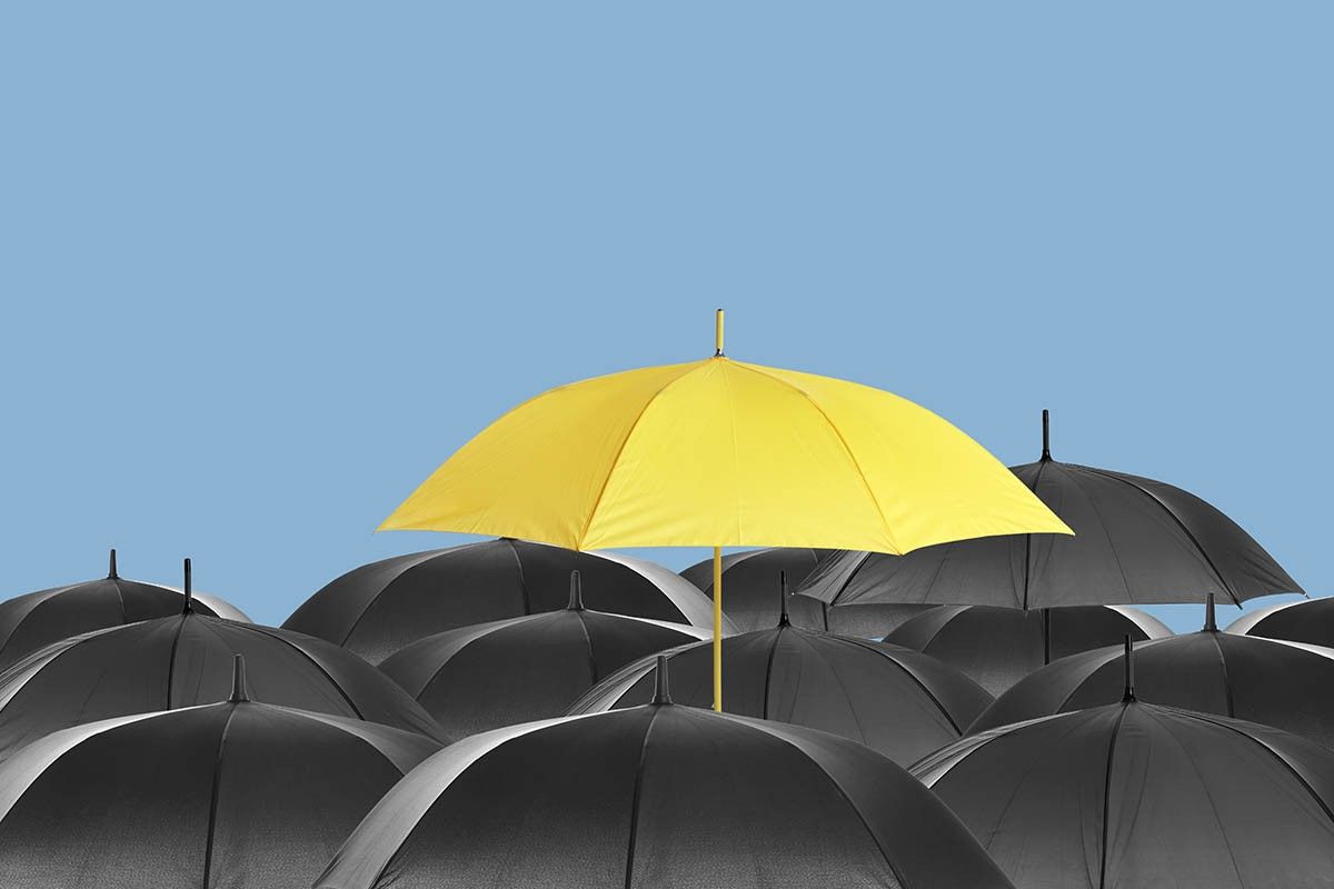 один яркий зонт среди одинаковых темных