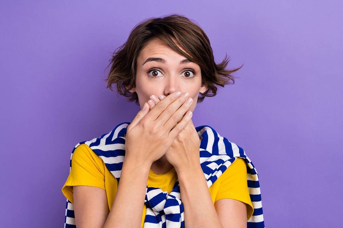 девушка закрывает рот руками